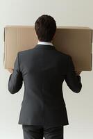 Businessman in suit carrying cardboard box on his shoulders in minimalist office space photo