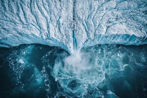 Aerial view of glacial iceberg calving into turquoise ocean water photo