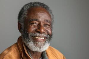 Smiling elderly Black man with gray beard, wearing a brown jacket, exuding warmth and wisdom against a neutral background. photo