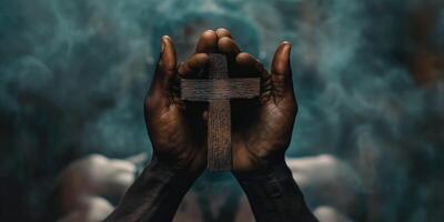 A pair of dark-skinned hands gently holding a rustic wooden cross, surrounded by a mystical, smoky backdrop. photo