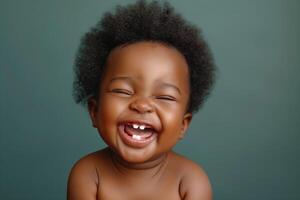 A joyful African American baby with curly hair, laughing and showing off two missing teeth against a soft teal background. photo