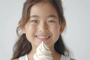A smiling Asian girl holds a delicious swirl of soft-serve ice cream, radiating joy and innocence. photo