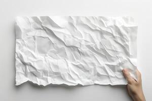 A hand holds a crumpled sheet of white paper against a clean, minimalistic background. photo