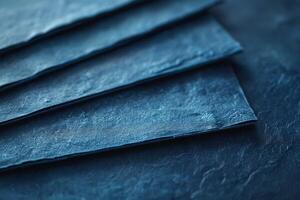 Close-up of layered dark blue textured paper sheets creating a moody and artistic composition. photo