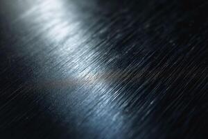 Close-up of textured metal surface reflecting light, showcasing intricate patterns and a dramatic interplay of shadows. photo