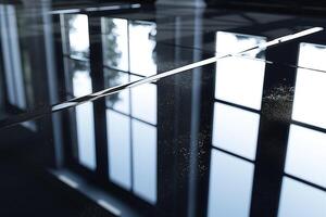 Close-up of polished black tile reflecting a window's light, creating a serene and modern ambiance. photo