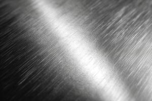 Close-up of polished stainless steel with reflective surface textures and subtle light streaks. photo