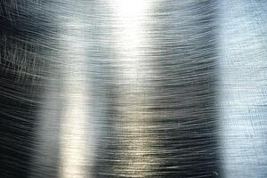 A close-up view of brushed metal, showcasing fine linear patterns and a reflective surface. photo