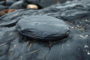 Close-up of a smooth, black stone sitting on textured rocks, showcasing natural beauty and intricate patterns. photo