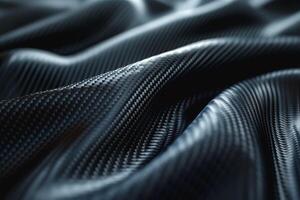 Close-up of textured black fabric resembling carbon fiber, showcasing intricate patterns and curves. photo