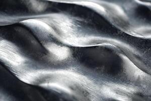 Close-up of textured metallic waves creating an abstract, dynamic composition. photo