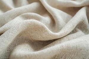 Close-up of textured, natural beige linen fabric, highlighting its soft, woven appearance. photo