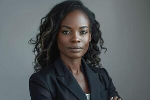 Confident Black woman in a tailored blazer, exuding professionalism and poise with arms crossed against a neutral backdrop. photo