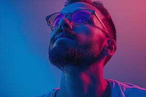 A young Hispanic man gazes upward, illuminated in striking pink and blue hues, showcasing a thoughtful expression. photo