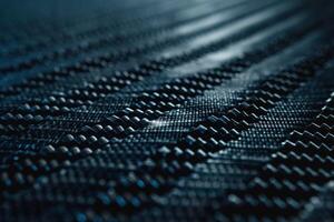 Close-up of textured carbon fiber material showcasing intricate patterns and shadows. photo