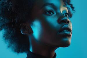 Portrait of a young Black woman with natural hair, illuminated in vibrant blue tones, showcasing her serene expression. photo