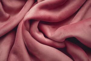 A close-up of soft, crumpled raspberry-colored fabric creating a rich and elegant texture. photo