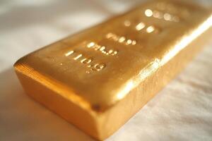 A close-up of a shiny gold bar resting on a soft white surface, exuding luxury and wealth. photo