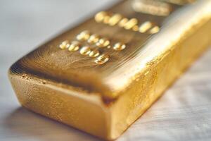 A close-up of a gleaming gold ingot showcasing its weight and purity, set against a soft background. photo