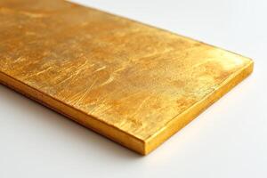 A shining gold bar resting on a smooth white surface, showcasing its luxurious texture and shimmering finish. photo