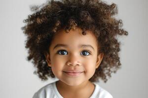 A smiling young girl with curly hair, showcasing innocence and joy against a soft, neutral background. photo