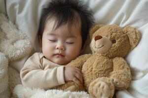 A peaceful Asian baby peacefully sleeping while hugging a soft teddy bear, surrounded by fluffy blankets. photo