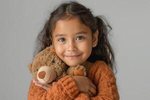 Smiling Hispanic girl embraces her teddy bear, showcasing warmth and affection in a cozy, neutral-toned setting. photo