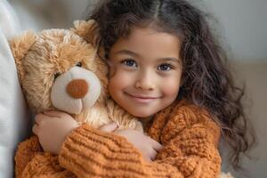 A joyful young girl of Middle-Eastern descent, hugging her soft teddy bear in a cozy, warmly lit setting. photo