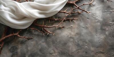 A delicate white fabric draped over sharp, barren branches on an earthy, textured surface. photo