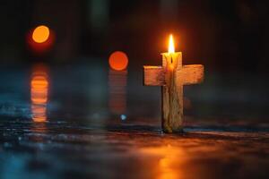 A lit candle shaped like a cross stands on a reflective surface, symbolizing hope and spirituality. photo