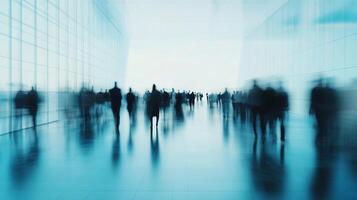 Blurred figures move through a bright, modern space, evoking a sense of motion and anonymity in a busy environment. photo