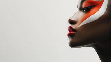 Striking profile of a woman with bold red and white makeup emphasizing her eye and face features, set against a minimalist background. photo