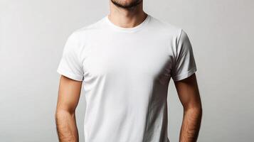 A man stands, his hands loosely placed in front of him, a stark white tee shirt creating a minimalist and casual appearance. photo