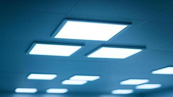 A suspended ceiling system with square-shaped LED panels emitting bright light in a bluish hue, creating uniform lighting and clean aesthetic photo