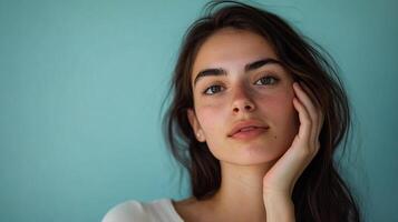 Close-up portrait of a woman with freckles and brown hair, posing against a light blue background with soft, natural lighting. photo