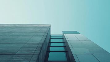 Abstract architectural shot showcasing converging building structures reaching towards a uniform, light teal sky. Modern aesthetics. photo
