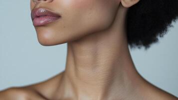 Close-up shot of a model's soft and smooth skin. The gloss on the lips gives them a shiny appearance. The dark hair contrasts with the light background. photo