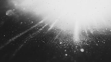 A black and white abstract image of light shining through particles, creating a textured and ethereal effect. Bokeh lights are captured. photo