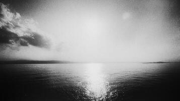 Monochromatic sea with diffused sunlight creating reflective patterns on the water surface and coastal lands visible afar. photo