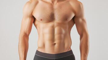 Torso of a muscular man displaying well-defined abdominal muscles, chest, and arms, showcasing fitness and health on a neutral background. photo