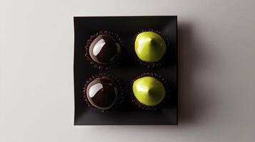 Three chocolate covered fruits in a black box photo