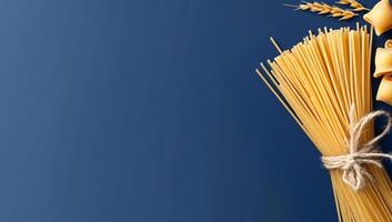 A bundle of spaghetti and pasta shapes on a blue background. photo