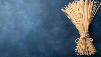 A bundle of uncooked spaghetti tied with twine on a textured background. photo