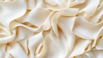 A close-up of soft, cream-colored fabric with elegant folds and drapes. photo