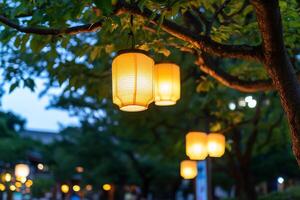 Lanterns hanging from branches, illuminating a serene evening setting. photo