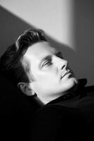 Dramatic black-and-white studio portrait with a single light source, deep shadows, strong contrasts photo