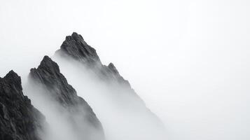 A monochrome mountain silhouette stands out against a deep foggy sky, casting a soft light and creating a dramatic atmosphere. photo