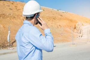 A Construction Worker Engaged in Phone Communication While at a Busy Job Site Environment photo