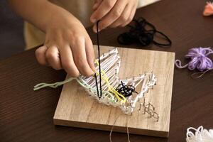 Child carefully wraps thread around tiny nails, building patience, focus, and artistic skills photo