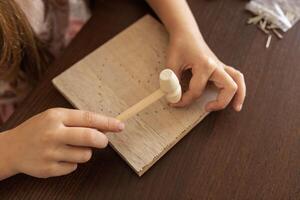Close-up of a child hands using hammer on wood. Crafting, learning, and building patience. photo